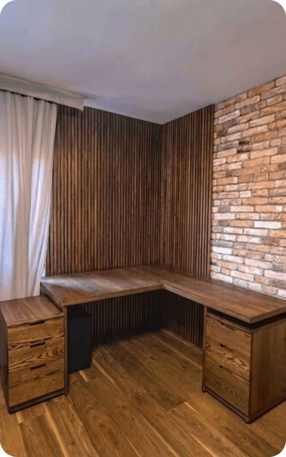 Birou de colț din lemn natur cu rollbox-uri integrate și perete decorativ cu riflaje