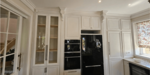 Mobilier bucătărie din lemn masiv în stil clasic alb, cu detalii sculptate, vitrine sticlă și încadrare electrocasnice
