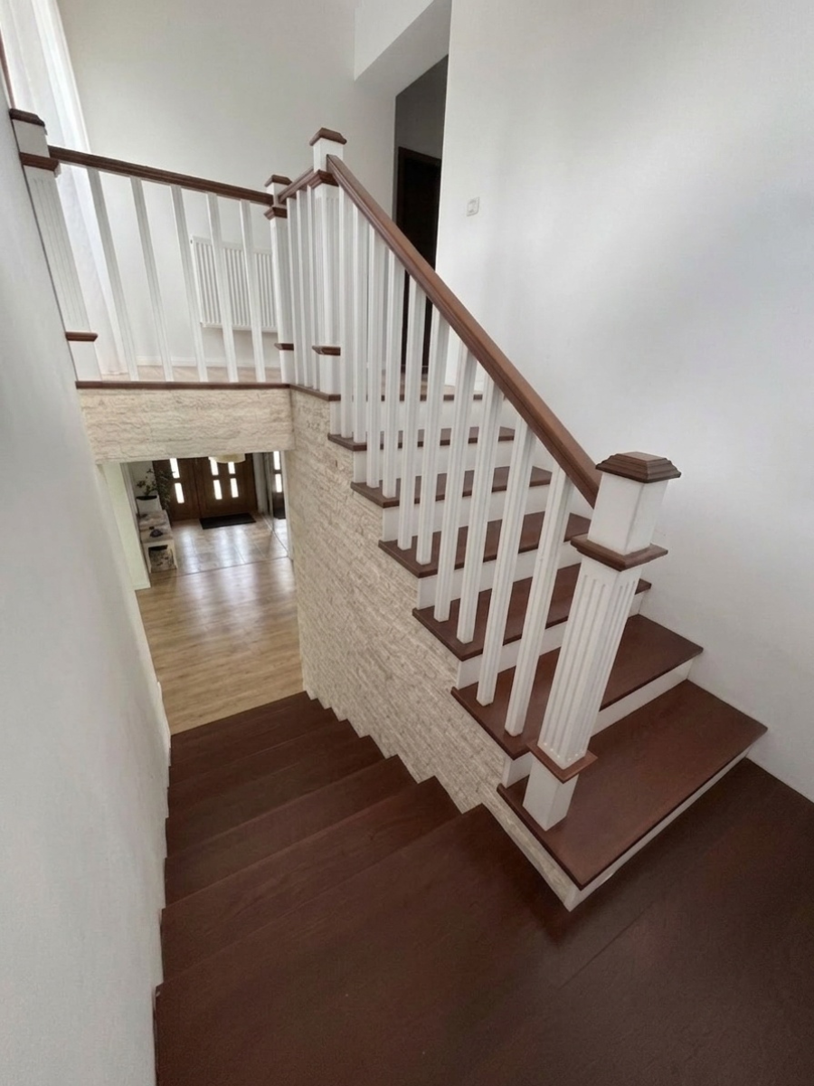 Ansamblu scară interioară din lemn cu contratrepte albe, balustradă din baluștri frezați și stâlpi decorativi de capăt