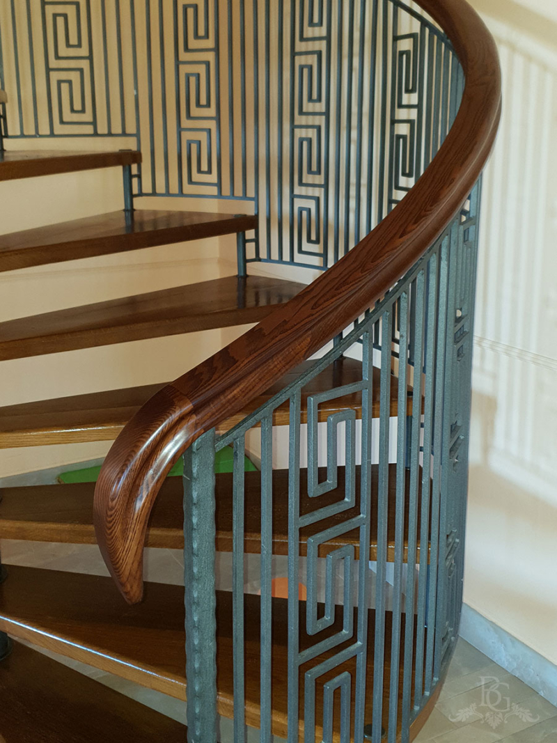 Detaliu mână curentă din lemn masiv nuc, elicoidală, și balustradă din fier forjat cu model geometric