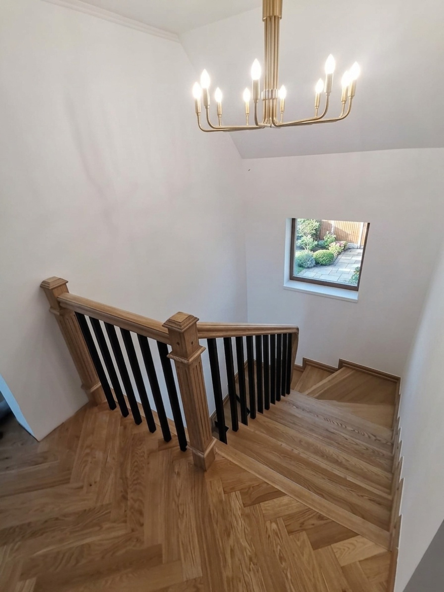 Scară interioară din lemn masiv natur cu balustradă modernă, baluștri negri și mână curentă din stejar